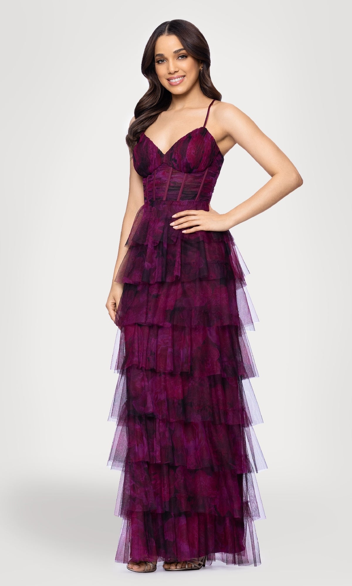 A woman stands and smiles against a plain background, wearing the Blondie Nites 5778BN Wine Red Ruffle Formal Gown: a sleeveless, floor-length dress with spaghetti straps and layered ruffles.